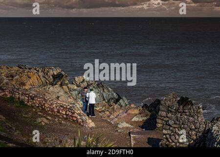 Alltag. Altes Paar, das vom felsigen Strand aus auf das Meer blickt. Stockfoto