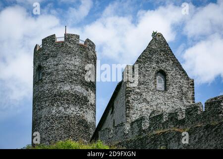 Bezdez, Tschechische Republik - Juli 19 2020: Blick auf einen Turm und ein Haus, Teile der mittelalterlichen Burg aus grauen Steinen auf einem felsigen Hügel. Sonnig. Stockfoto