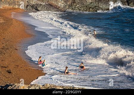 Alltag. Eine Gruppe von Damen, die am Strand der Stadt sitzen und große Wellen surfen Stockfoto