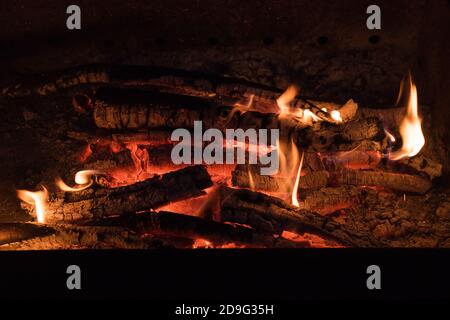 Feuer in einem Kamin aus Feuerholz. Brennende Baumstämme in einem kleinen Lagerfeuer. Stockfoto