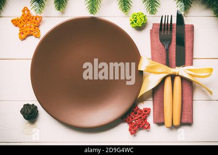 Blick von oben auf das neue Jahr Abendessen auf festliche Holz- Hintergrund. Zusammensetzung der Teller, Gabel, Messer, Tannenbaum und Dekorationen. Frohe Weihnachten Konzept. Stockfoto