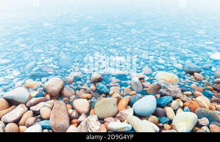 Flusssteine oder Kieselsteine am Flussufer und am Wasser. Stockfoto