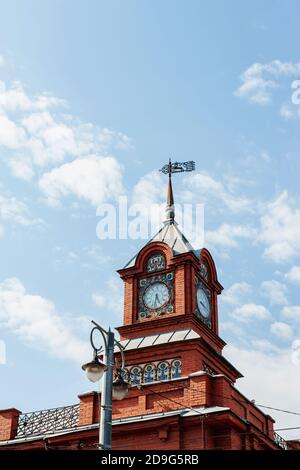 Fragment des oberen Teils des historischen Gebäudes mit einem Turm zeigt die Schönheit der Backsteinsakralen Architektur. Eine große Uhr und ein Metall Stockfoto