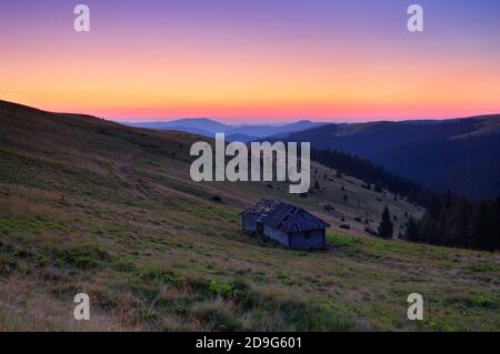 Sonnenaufgang in den Bergen mit einsamem Holzhaus Stockfoto