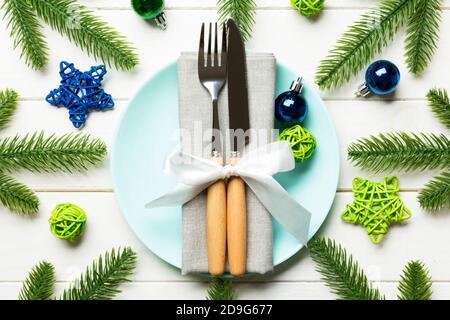 Blick von oben auf das neue Jahr Abendessen auf festliche Holz- Hintergrund. Zusammensetzung der Teller, Gabel, Messer, Tannenbaum und Dekorationen. Frohe Weihnachten Konzept.