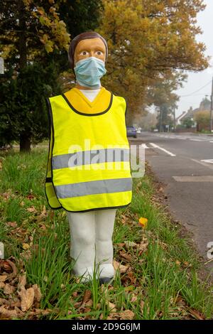 Iver, Buckinghamshire, Großbritannien. November 2020. Ein Fußgänger-Sicherheitsmodell der Kinderschule neben einer Fußgängerüberfahrt trägt eine Gesichtsmaske und einen gut sichtbaren Tabard. Obwohl England in eine Covid-19-Sperre gegangen ist, sind die Schulen noch offen. Alle älteren Kinder und Lehrer in Schulen sind nun verpflichtet, Gesichtsmasken tragen. Quelle: Maureen McLean/Alamy Live News Stockfoto