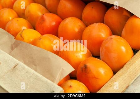 Frische Bio reife Kaki in einer Holzkiste vor dem Versand auf den Markt. Nahaufnahme. Stockfoto