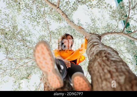 Frau genießt es, einen Baum zu klettern. Freiheitskonzept Stockfoto