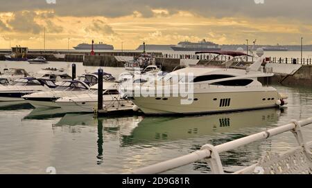 Torquay Marina unter bedrohlichem Himmel, mit drei Kreuzfahrtschiffen in Tor Bay während der Coronavirus-Pandemie vor Anker. Stockfoto