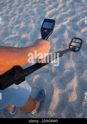 Der Mensch nutzt den Metalldektor am Strand, um nach wertvollen Objekten zu suchen, Gonnesa, im Süden sardiniens Stockfoto