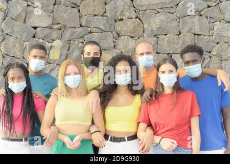 Millennial Menschen aus verschiedenen Kulturen und Rassen Blick auf Kamera mit Schutzmasken für Coronavirus . Studenten haben Spaß an der erasmus-Universität. Stockfoto