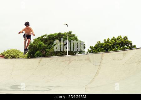 Skater Jungen Training in der Stadt Skatepark im Freien. Junge trendige Mann Durchführung Fähigkeiten und Tricks mit speziellen Kick Scooter. Extremsportkonzept - IMAG Stockfoto