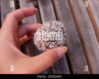 Hand hält eine köstliche schwedische Schokolade Kugel. Auch bekannt als havreboll, kokosboll und negerboll, chokladbollar ist eine Schokolade und Kokosnuss Cupcake fr Stockfoto