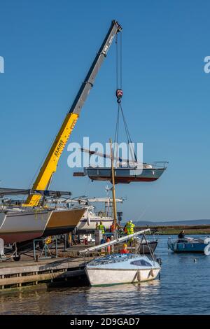 Eine Yacht, die von einem Kran an einer Segelyacht an der Südküste im Hafen von christchurch für einen Winter-Anti-Foul und Peeling aus dem Wasser gehoben wird. Stockfoto