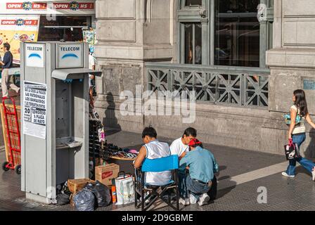 Buenos Aires, Argentiana - 19. Dezember 2008: Ambulanter Sonnenbrillen-Verkäufer sitzt in der Nähe nicht mehr funktionierten Telefonzelle der Telecom in Retiro Station auf Ave dr. José Stockfoto