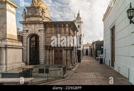 Buenos Aires, Argentiana - 19. Dezember 2008: Friedhof La Recoleta. Gasse zwischen monumentalen Mausoleen, unter blauer Wolkenlandschaft. Stockfoto