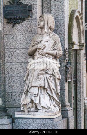 Buenos Aires, Argentiana - 19. Dezember 2008: Friedhof La Recoleta. Nahaufnahme einer jungen Frau mit Kreuzstatue aus weißem Stein auf der Seite von Ramon Andres Leg Stockfoto