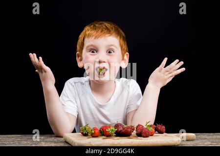 Ein Junge isst reife Erdbeeren Stockfoto