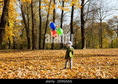 Schöner Junge mit einem roten, grünen und blauen Ballon Stockfoto