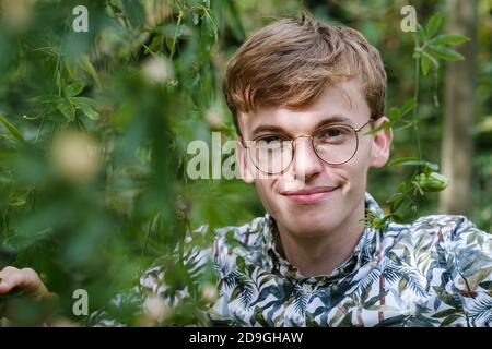 Junge kaukasische Männchen mit Brillen in einem Garten posieren Stockfoto