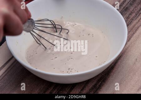 Mischen Sie den perfekten Hefeteig in der weißen Schüssel auf Der Holztisch Stockfoto