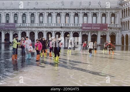 Touristen fotografieren auf dem Markusplatz bei Flut, Acqua alta, mit Blick auf die San Marco Procuratie Stockfoto