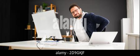 Junger Mann Mit Rückenschmerzen. Falsche Bürohaltung Stockfoto