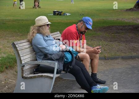 AUCKLAND, NEUSEELAND - 01. Nov 2020: Blick auf das Paar, das auf der Bank im Park sitzt Stockfoto