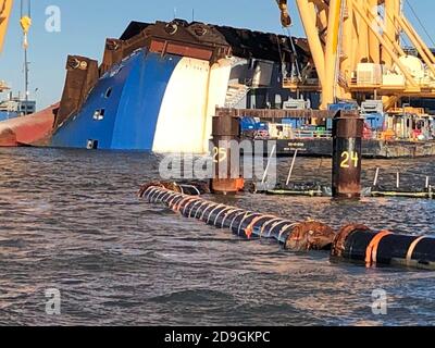 Arbeiter installieren Umweltschutzbarrieren rund um das Wrack des Golden Ray-Schiffes, um den Bergungsbetrieb am 30. Oktober 2020 in St. Simons, Georgia, zu beginnen. Der riesige Autoträger Frachtschiff kenterte 4,200 mit 2019 Autos in den Ladedecks. Stockfoto