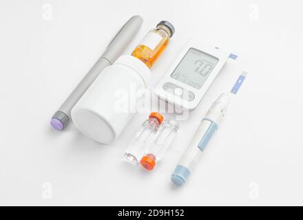 Glucometer, Lanzetten, Pillen und Insulinflaschen auf weißem Hintergrund. Diabetes-Konzept Stockfoto