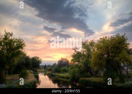 In der Nähe des Sonnenuntergangs schien die Sonne durch vereinzelte Wolken und Dunst durch Rauch von Waldbränden in den fernen Bergen verursacht. Stockfoto