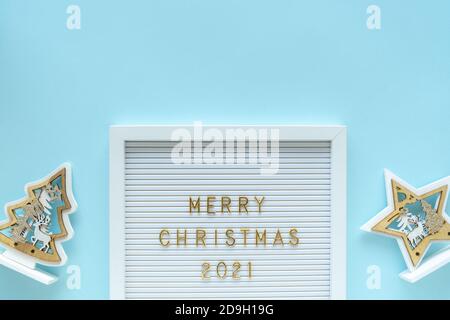 Briefbrett mit Frohe Weihnachten 2021 Gruß, Dekorationen auf blauen Pastell girly Hintergrund. Weihnachtskomposition. Flach legen, von oben Stockfoto