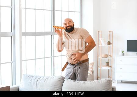 Übergewichtiger Mann essen Pizza zu Hause. Gewichtsverlust Konzept Stockfoto