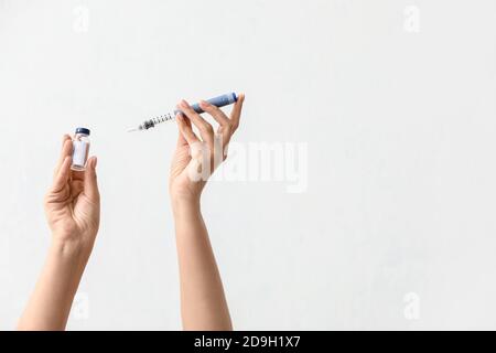 Weibliche Hände mit Insulinflasche und Spritze auf hellem Hintergrund. Diabetes-Konzept Stockfoto