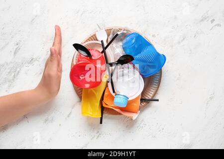 Weibliche Hand mit Plastikmüll zeigt Stop-Geste auf weißem Hintergrund. Ökologie-Konzept Stockfoto