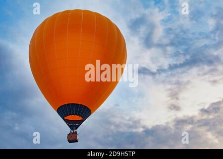 Orangefarbener Ballon gegen bewölkten Himmel Stockfoto