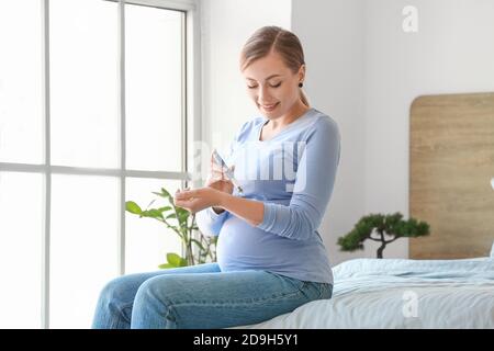 Schwangere Diabetikerin, die sich zu Hause Insulinspritze gibt Stockfoto