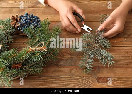 Frau, die schönen Weihnachtskranz auf dem Tisch Stockfoto