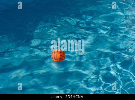 Orange Volleyball schwimmt auf dem Wasser im Schwimmbad auf Ein Sommertag Stockfoto
