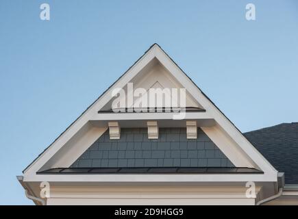 Einzel- und Doppelkiebel-Dächer mit Backstein- oder Vinylgleitviereck und ovalen Dachfenstern mit blauem, neutralem Himmel-Hintergrund Stockfoto