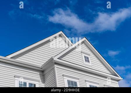 Colonial White Double Peak Giebel weißen Rahmen elegante Flügel Fenster dekorative Reise, Soffit auf einem neuen amerikanischen Haus in einer neuen Nachbarschaft Straße in der Stockfoto