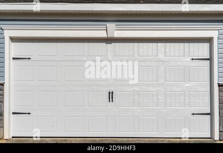 Doppelauto klassisch isolierter Stahl erhöhte Panel Garagentor mit einem weißen Trimm, um Akzent, auf einem neuen amerikanischen Haus Stockfoto