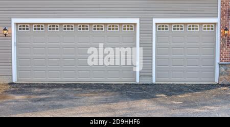 Zwei Autos und ein Auto anthrazit klassisch isoliert Stahl erhöhte Panel Garagentor mit einer weißen Blende, um Akzent, mit Heckspiegel Licht gerahmt Stockfoto