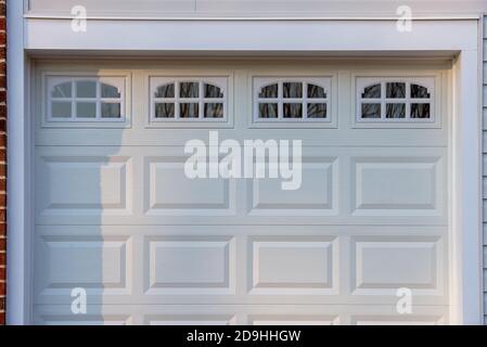 Doppelauto klassisch isolierter Stahl erhöhte Panel Garagentor mit einem weißen Trimm, um Akzent hinzuzufügen eingerahmt, w / Heckspiegel Lichtfenster durch muntins auf einem n geteilt Stockfoto