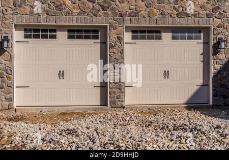 Nahaufnahme von hellem Ahorn oder Wüstenbraun Triple Single Auto isoliert Stahl erhöhte Panel Garagentor und Vinyl horizontal Lap Siding auf einem brandneuen gebaut Stockfoto