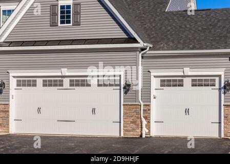 Doppelauto klassisch isolierter Stahl erhöhte Panel Garagentor mit einem weißen Trimm, um Akzent, auf einem neuen amerikanischen Haus Stockfoto