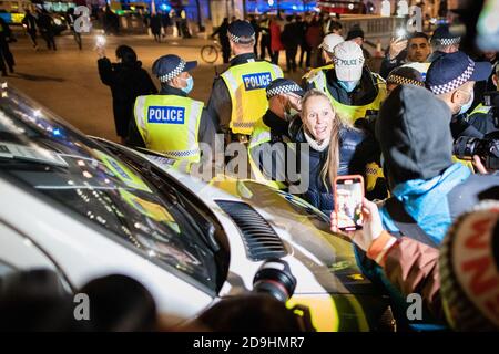 London, Großbritannien. November 2020. Eine Frau wird von der Polizei festgenommen, während sich Demonstranten während der Demonstration am Trafalgar Square versammeln.die Bewegung "Erwarten wir" nimmt an ihrem jährlichen Millionen-Maskenmarsch Teil. Die Anonymous-Bewegung zeigt Solidarität für eine Gesellschaft, die von der politischen Elite und den assoziierten Unternehmen marginalisiert wird. Kredit: SOPA Images Limited/Alamy Live Nachrichten Stockfoto