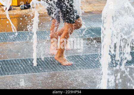 Verschwommene Laufbeine durch Wasserbrunnen vom Boden, Lifestyle-Konzept, Kindheit glückliche Zeit. Stockfoto