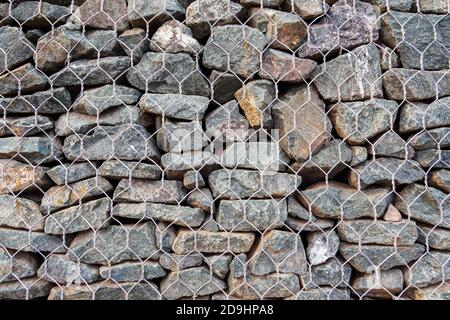 Zaun aus Steinen in Metallgeflecht, Nahaufnahme von Gabion für den Einsatz im Tiefbau, Straßenbau Landschaftsbau. Stockfoto