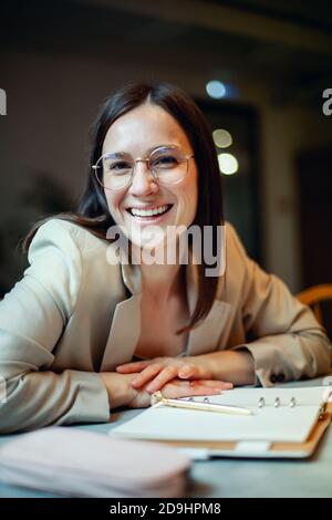 Schöne junge Frau in Anzug schriftlich ihre Business-Pläne, während Kaffee trinken in der Pause Stockfoto